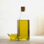 Bol y botella de cristal transparente con aceite de oliva
